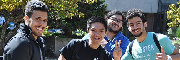 Four international students smiling and waving at the camera